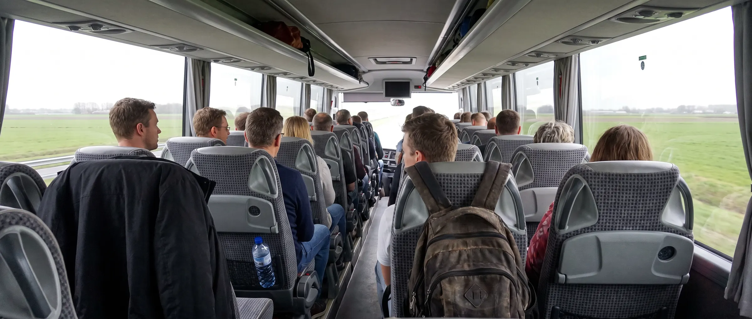 Passagiers onderweg in een touringcar, gezien vanuit het gangpad